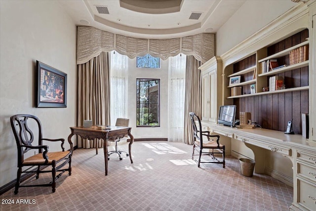 office space with built in desk and a raised ceiling