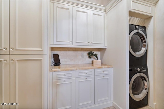 clothes washing area featuring cabinets and stacked washer / dryer