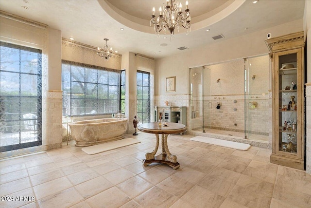 bathroom featuring tile patterned floors, separate shower and tub, a raised ceiling, and tile walls