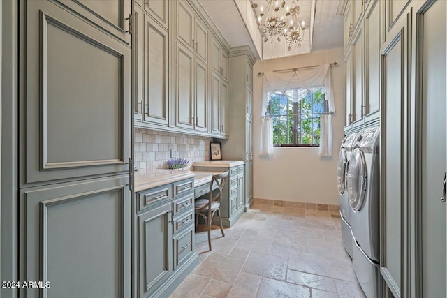 clothes washing area featuring cabinets, a notable chandelier, and washing machine and clothes dryer