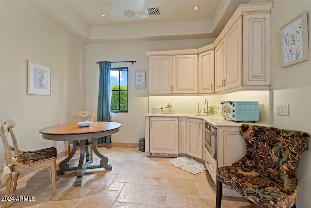 kitchen featuring oven, sink, and cream cabinets