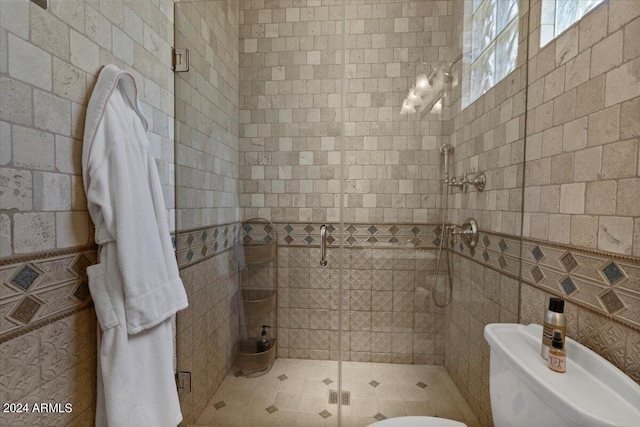 bathroom with an enclosed shower, toilet, and tile walls