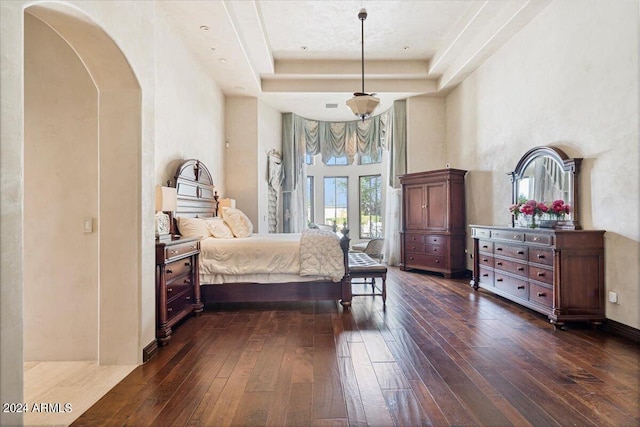 bedroom featuring a tray ceiling, a towering ceiling, and dark wood-type flooring