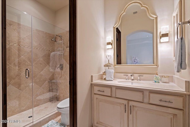 bathroom with vanity, toilet, and a shower with door