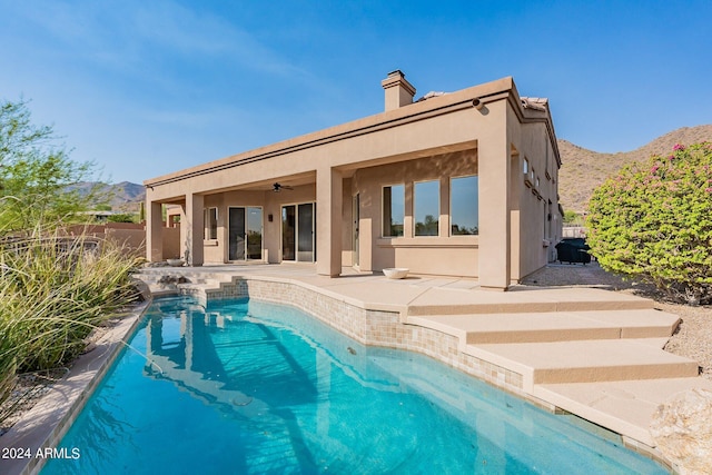 rear view of house with ceiling fan, a fenced in pool, a mountain view, and a patio