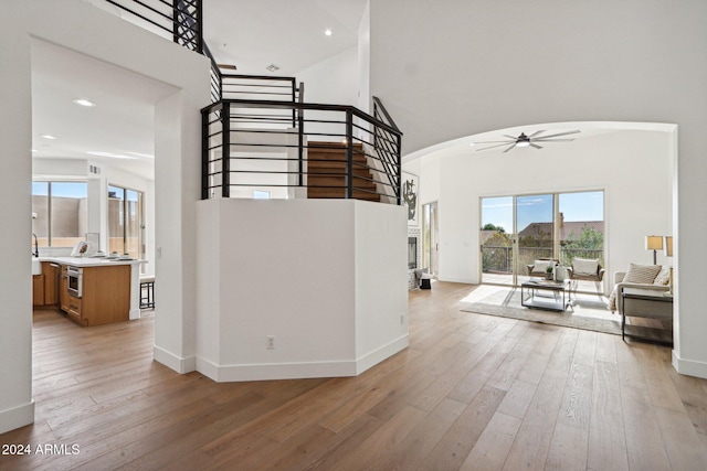 staircase with a high ceiling, ceiling fan, and wood-type flooring