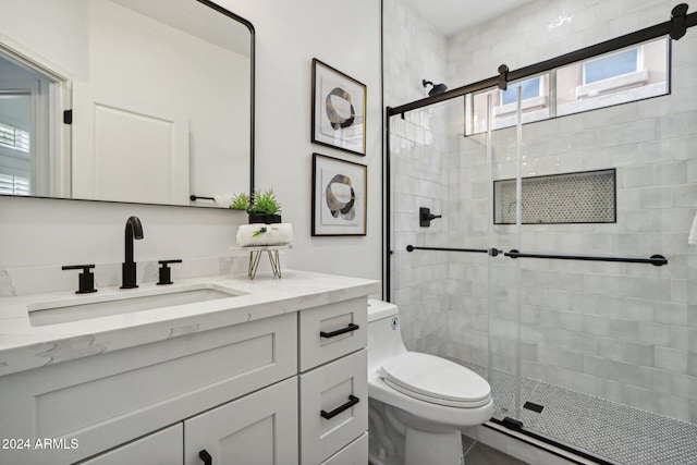 bathroom with a shower with door, vanity, and toilet