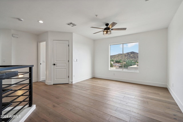 unfurnished room featuring ceiling fan, a mountain view, and light hardwood / wood-style floors