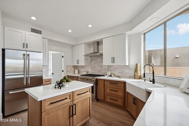 kitchen with white cabinetry, sink, a healthy amount of sunlight, wall chimney range hood, and high end appliances