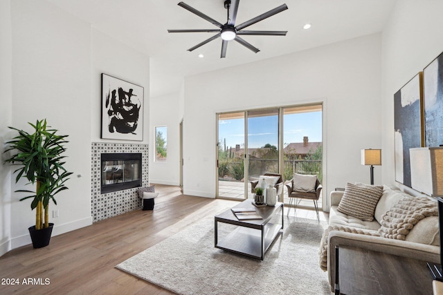 living room with a tile fireplace, ceiling fan, and light hardwood / wood-style flooring