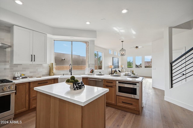 kitchen featuring white cabinetry, sink, hanging light fixtures, appliances with stainless steel finishes, and light wood-type flooring