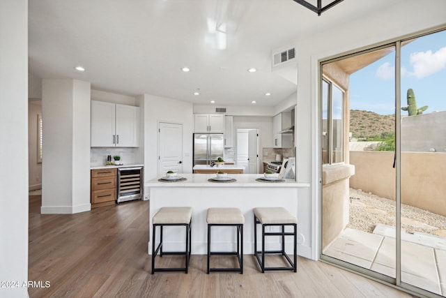 kitchen with hardwood / wood-style floors, stainless steel built in fridge, white cabinetry, and beverage cooler