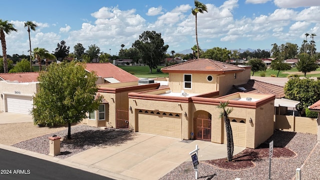 mediterranean / spanish home featuring concrete driveway, a tiled roof, an attached garage, and stucco siding