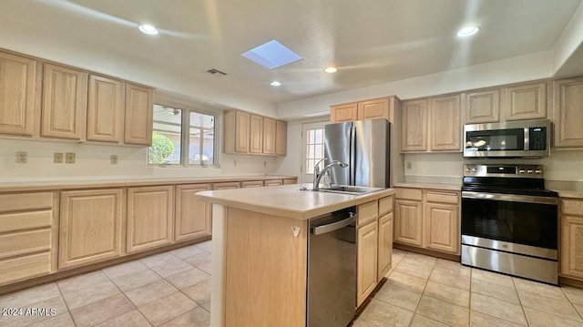 kitchen featuring stainless steel appliances, light brown cabinets, a kitchen island with sink, and sink