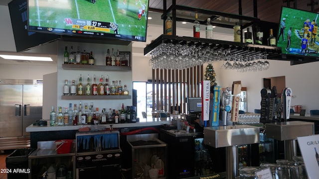 bar featuring stainless steel fridge with ice dispenser