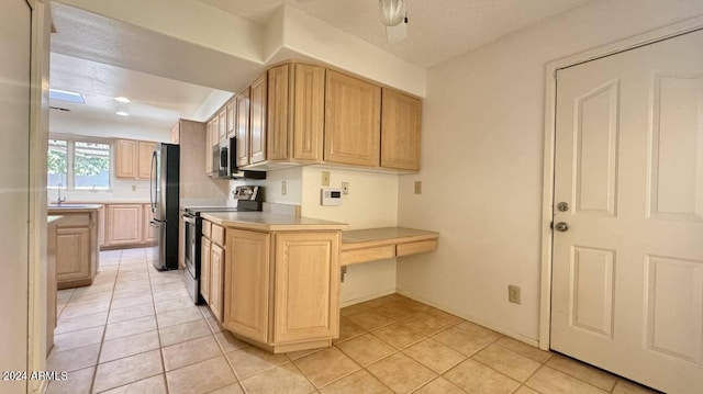 kitchen featuring a textured ceiling, light brown cabinets, light tile patterned floors, and stainless steel appliances