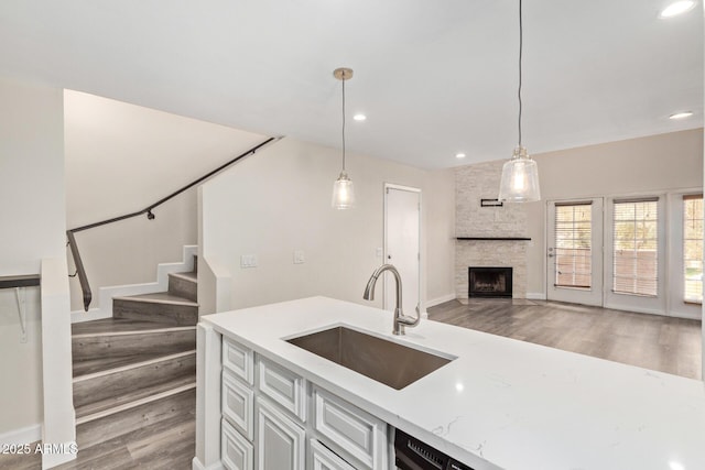 4901 S Calle Los Cerros Dr Unit 220, Tempe, AZ 85282 - kitchen featuring a sink, light wood-type flooring, a stone fireplace, open floor plan, and hanging light fixtures