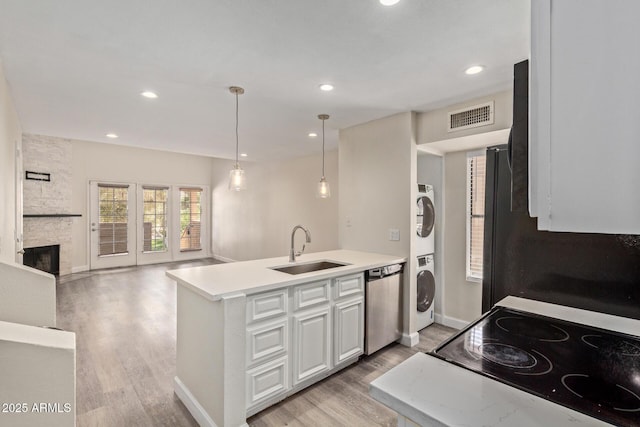 4901 S Calle Los Cerros Dr Unit 220, Tempe, AZ 85282 - kitchen with stainless steel dishwasher, a sink, stacked washing machine and dryer, a peninsula, and light wood-type flooring
