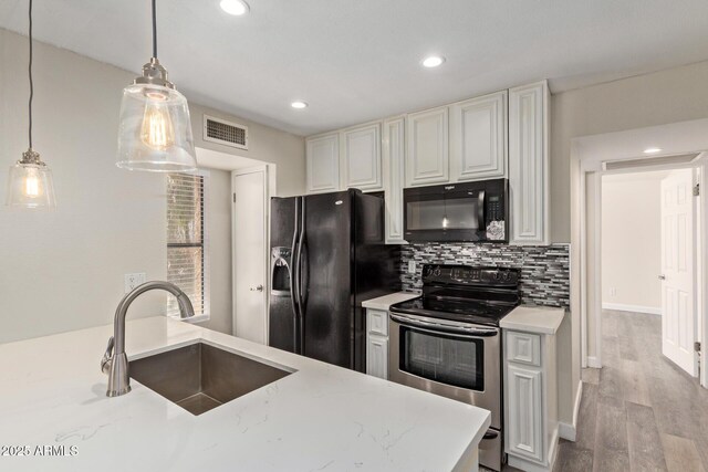 4901 S Calle Los Cerros Dr Unit 220, Tempe, AZ 85282 - kitchen featuring black appliances, a sink, wood finished floors, backsplash, and decorative light fixtures