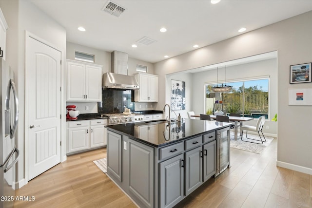 kitchen featuring sink, gray cabinets, a kitchen island with sink, white cabinets, and beverage cooler