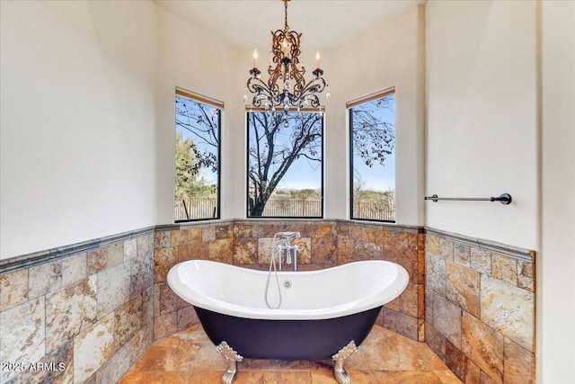 bathroom with a chandelier, tile walls, and a tub