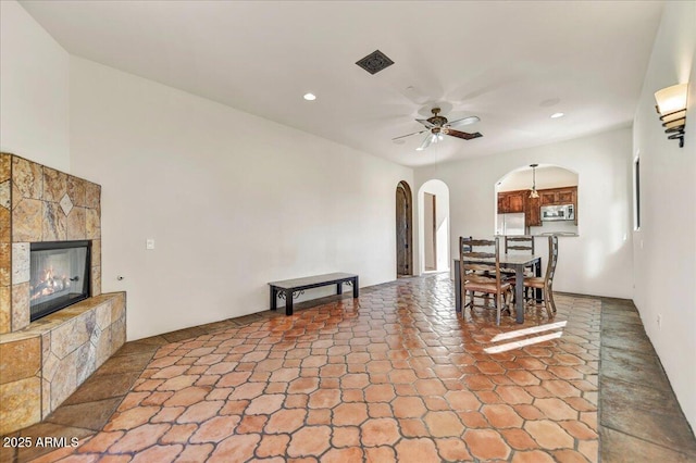 dining space featuring ceiling fan and a stone fireplace