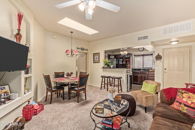 carpeted living room with ceiling fan with notable chandelier and a skylight