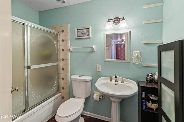 bathroom featuring enclosed tub / shower combo, toilet, and baseboards