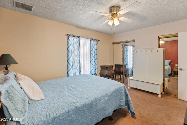 bedroom featuring a ceiling fan, visible vents, a textured ceiling, and carpet flooring