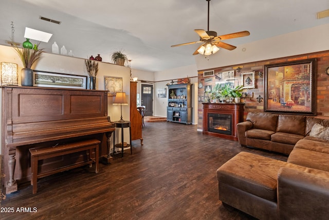 living room featuring ceiling fan, a glass covered fireplace, wood finished floors, and visible vents