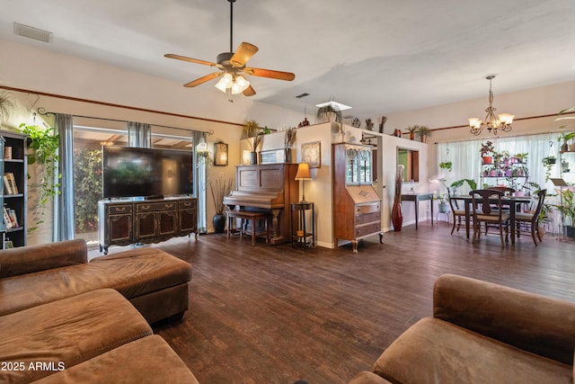 living area with ceiling fan with notable chandelier, wood finished floors, and visible vents