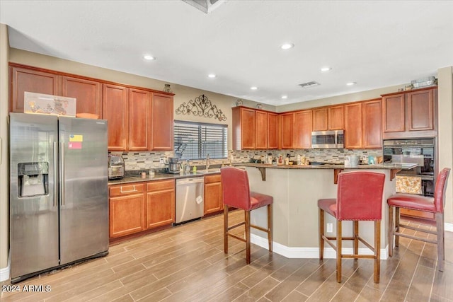 kitchen featuring sink, a center island, stainless steel appliances, light hardwood / wood-style flooring, and a breakfast bar