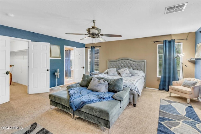 carpeted bedroom with a walk in closet, ceiling fan, a closet, and ensuite bathroom