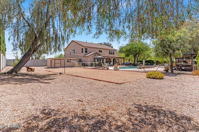 rear view of property with a fenced in pool and a shed