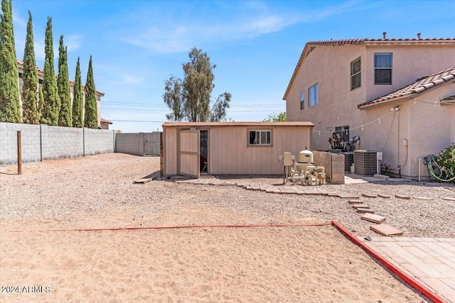 rear view of house with central AC unit and a storage unit