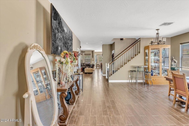 entryway featuring hardwood / wood-style flooring, a textured ceiling, and a chandelier