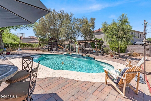 view of swimming pool featuring a pergola, pool water feature, a playground, and a patio area