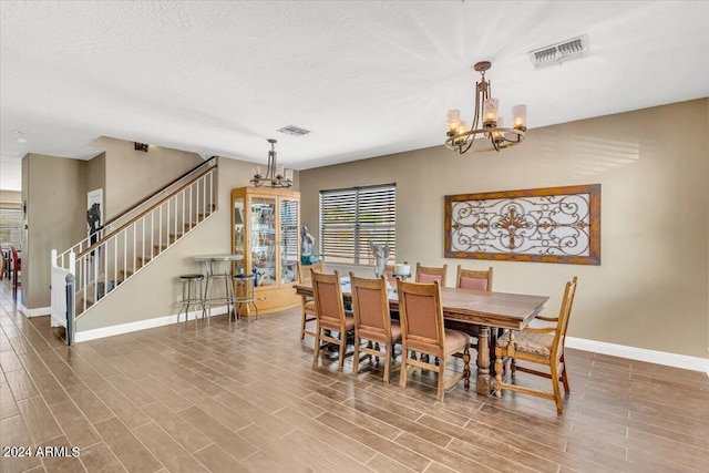 dining room featuring hardwood / wood-style floors, a textured ceiling, and a notable chandelier