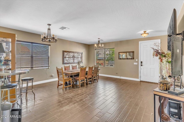 dining space with a chandelier, a textured ceiling, and hardwood / wood-style flooring