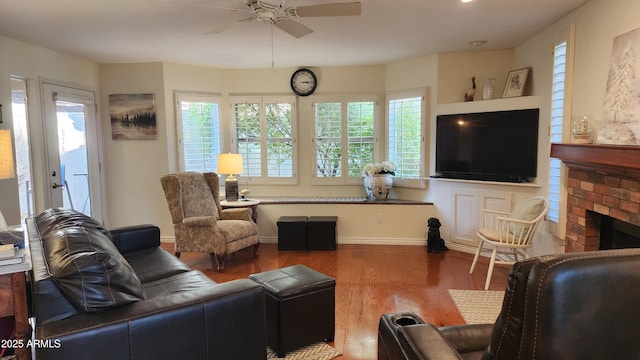 living room featuring a fireplace, wood-type flooring, a healthy amount of sunlight, and ceiling fan