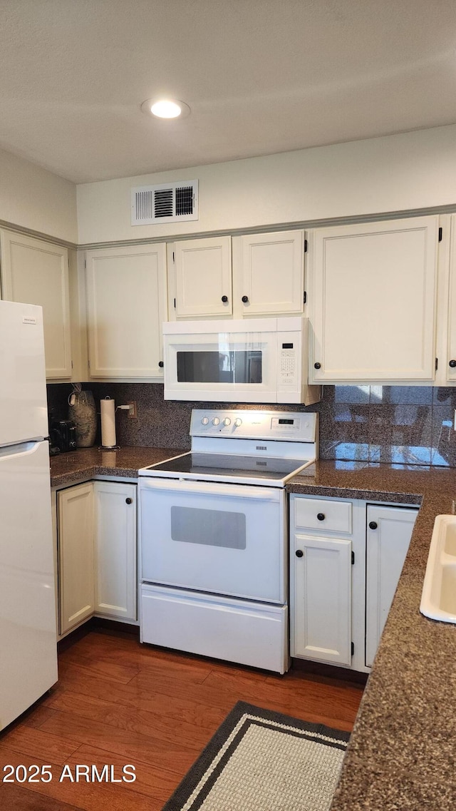 kitchen with tasteful backsplash, white appliances, dark hardwood / wood-style flooring, and white cabinets