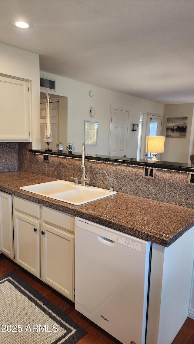 kitchen with sink, dark wood-type flooring, white dishwasher, tasteful backsplash, and white cabinets