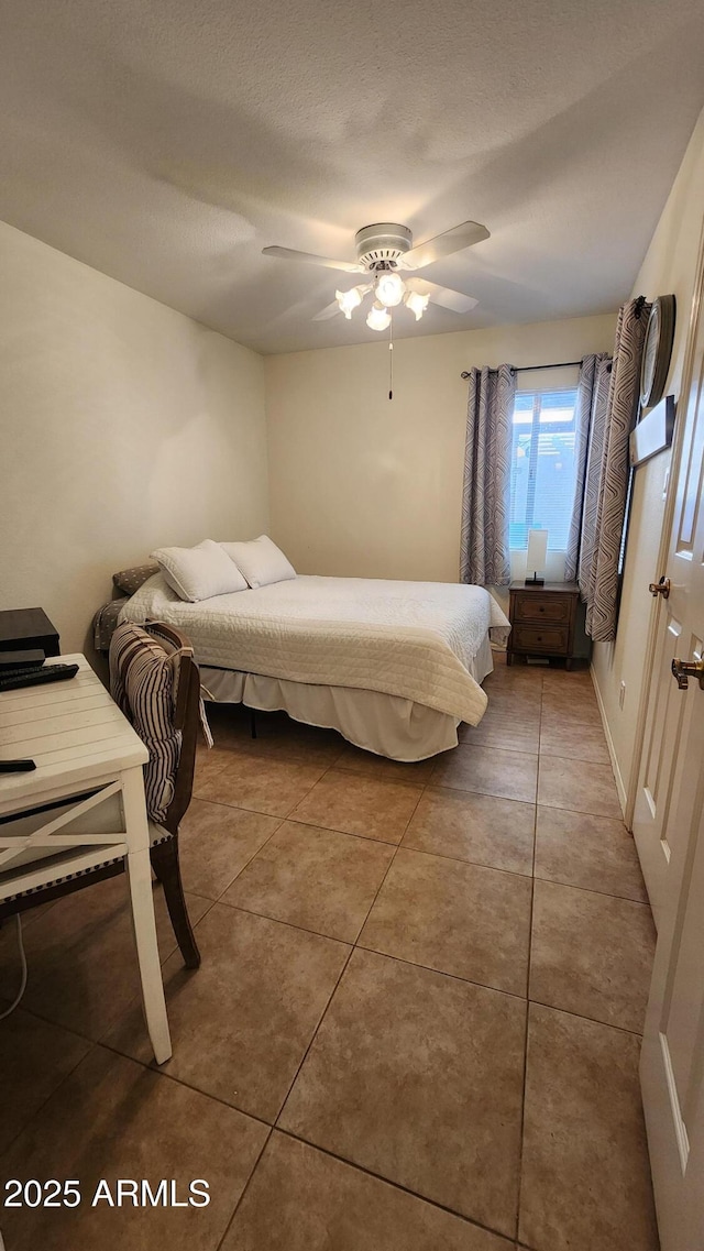 bedroom with ceiling fan, tile patterned flooring, and a textured ceiling