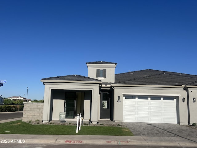view of front of property with an attached garage, driveway, and stucco siding