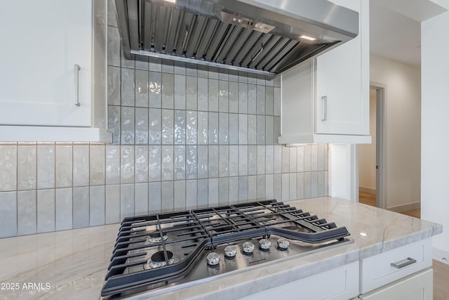 kitchen featuring premium range hood, stainless steel gas cooktop, light stone counters, decorative backsplash, and white cabinets
