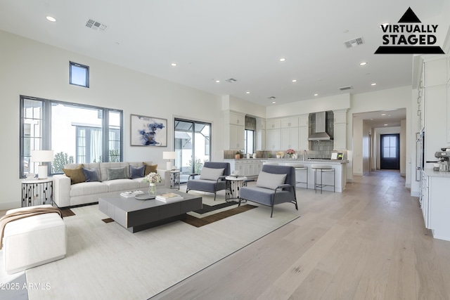 living area with ornate columns, light wood-style flooring, and recessed lighting