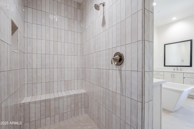 bathroom with tiled shower, a sink, and recessed lighting