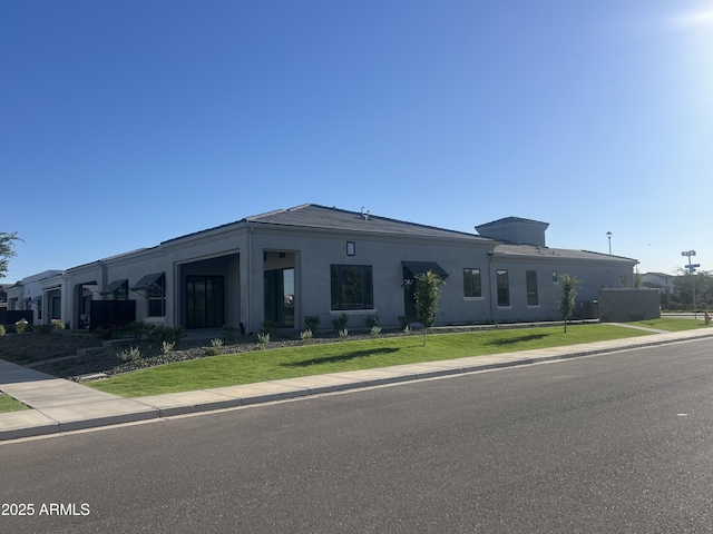 view of front of house featuring stucco siding and a front lawn