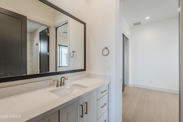 bathroom featuring wood finished floors, vanity, baseboards, and recessed lighting
