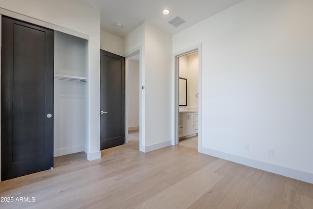unfurnished bedroom featuring light wood-style floors, a closet, baseboards, and connected bathroom